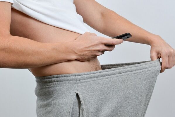 mężczyzna spogląda w dół spodni i widzi powiększonego penisa